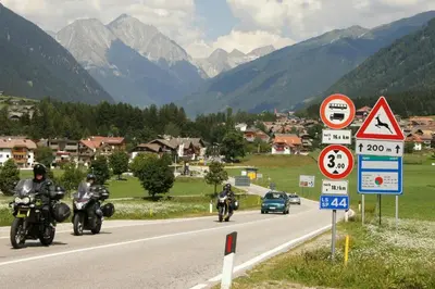 a group of motorcycles driving down a road with mountains at Pizzeria Restaurant Wieser in Rasùn di Sotto