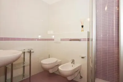 a white bathroom with a toilet and a sink at Pizzeria Restaurant Wieser in Rasùn di Sotto