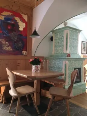 a dining room with a table and chairs and a fireplace at Hotel Garnì Salvanel in Cavalese