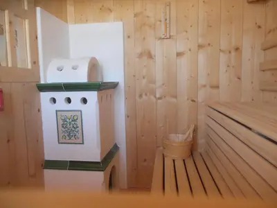 a wooden cabin with a stove and a trash can at Hotel Garnì Salvanel in Cavalese