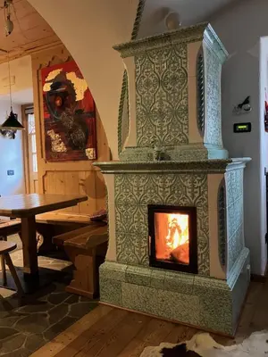 a large stone fireplace in a room with a table at Hotel Garnì Salvanel in Cavalese