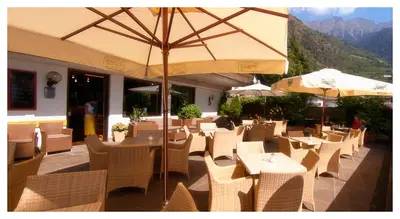 a restaurant with tables and chairs and an umbrella at Apparthotel Taufenbrunn in Parcines