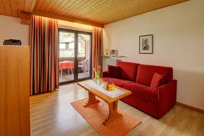 a living room with a red couch and a table at Apparthotel Taufenbrunn in Parcines