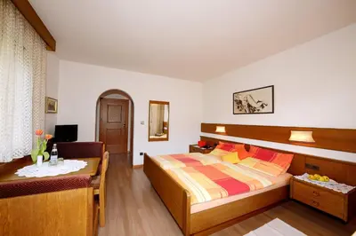 a bedroom with a bed and a table and a chair at Apparthotel Taufenbrunn in Parcines