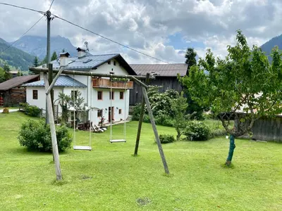 a yard with swings in front of a house at Dolomites Charme Chalet in Colle Santa Lucia