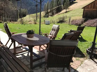 a patio table and chairs with a potted plant on it at Dolomites Charme Chalet in Colle Santa Lucia