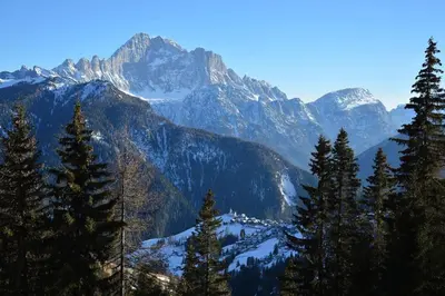 a mountain range with trees and snow covered mountains at Dolomites Charme Chalet in Colle Santa Lucia