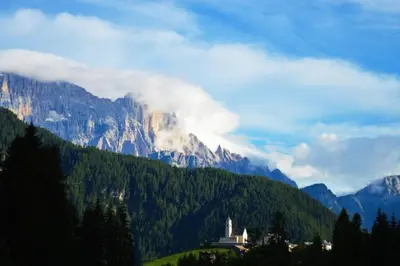 a castle on a hill in front of a mountain at Dolomites Charme Chalet in Colle Santa Lucia