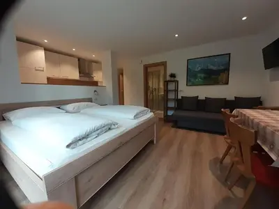 a bedroom with a large white bed and a living room at Prensanueva in Santa Cristina in Val Gardena