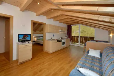 a kitchen and living room with a couch in a room at Prensanueva in Santa Cristina in Val Gardena