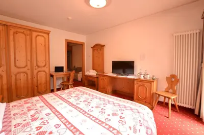 a bedroom with a large bed and a television at Hotel La Montanina in Alleghe