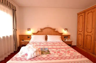 a bedroom with a large bed with a wooden headboard at Hotel La Montanina in Alleghe