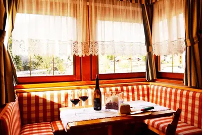 a restaurant with a table and two glasses of wine at Hotel La Montanina in Alleghe