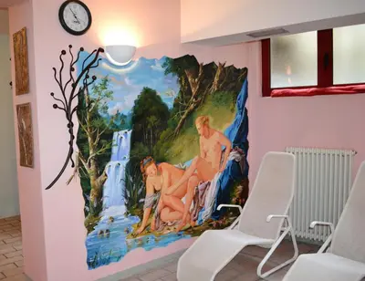 a mural on a wall in a room with chairs at Hotel La Montanina in Alleghe