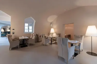 a dining room with white chairs and tables and a window at Castel Hörtenberg in Bolzano