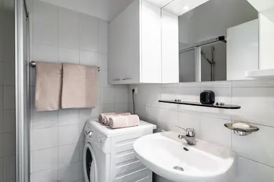 a white bathroom with a sink and a washing machine at Apartment Villa Schmid in Bolzano