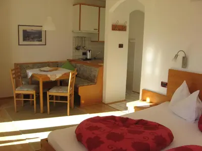 a room with a bed and a table and a kitchen at Pension Chalet Andy in Schenna