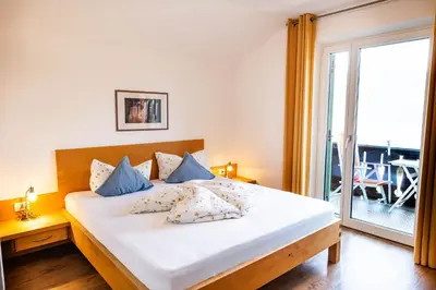 a bedroom with a large white bed with blue pillows at Pension Chalet Andy in Schenna