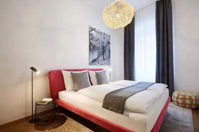 a bedroom with a large bed with a red headboard at Arte Apartments in Bolzano
