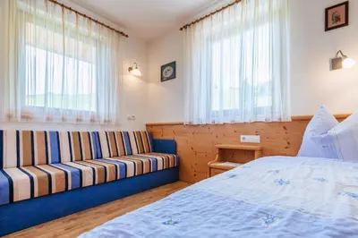 a bedroom with a couch and a bed and windows at Residence Speckerhof in Maranza