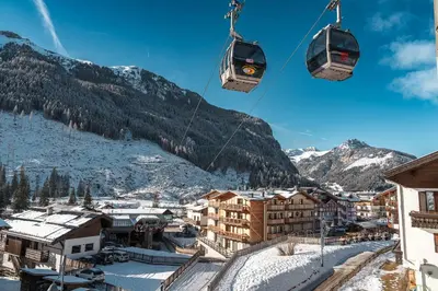 a ski lift over a town with snow covered mountains at Cesa Planber Apartments Mountain View SKI-IN SKI-OUT in Canazei