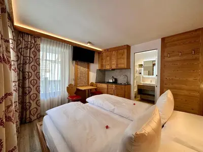 a bedroom with two beds and a kitchen at Cesa Planber Apartments Mountain View SKI-IN SKI-OUT in Canazei
