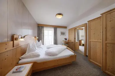 a bedroom with a bed with white sheets and pillows at Garni-Hotel Tritscherhof in Tirolo
