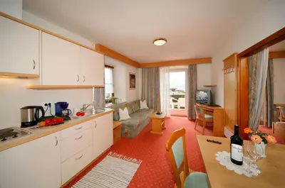 a kitchen with white cabinets and a table with a bottle of wine at Garni-Hotel Tritscherhof in Tirolo
