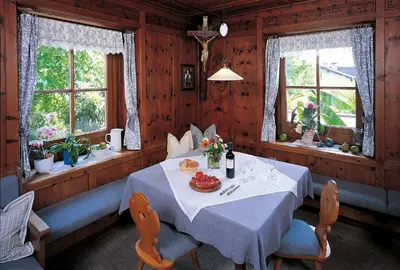 a dining room with a table and two windows at Garni-Hotel Tritscherhof in Tirolo