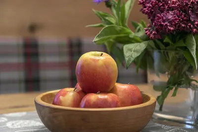 a bowl of apples on a table with a vase of flowers at Garni-Hotel Tritscherhof in Tirolo