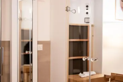 a glass shower door in a bathroom with a sink at Parkhotel Tirolerhof in Lagundo