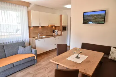 a living room with a table and a kitchen at Ferienwohnungen Burgwies in San Martino