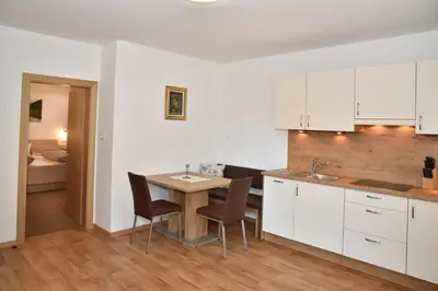 a kitchen with white cabinets and a table and chairs at Ferienwohnungen Burgwies in San Martino
