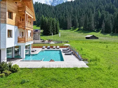 a house with a swimming pool in a field at Hotel Pozzamanigoni in Selva di Val Gardena