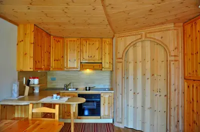 a kitchen with wooden cabinets and a wooden table at Apartment Sissi in Badia