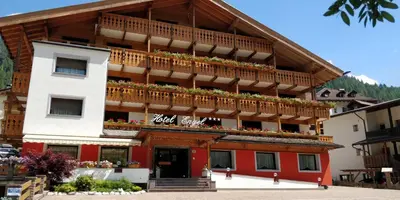a building with a balcony with flowers on it at Hotel Engel in Canazei