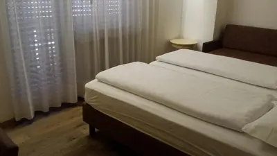 a bedroom with a bed and a window with curtains at Hotel Engel in Canazei