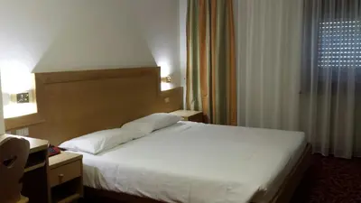 a bedroom with a white bed and a window at Hotel Engel in Canazei