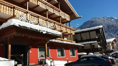 a snow covered building with a car parked in front at Hotel Engel in Canazei