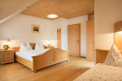a bedroom with two beds and wooden floors at Peterer Hof in Rasùn di Sotto