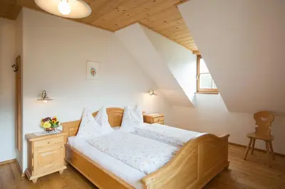 a bedroom with a wooden bed with white sheets at Peterer Hof in Rasùn di Sotto
