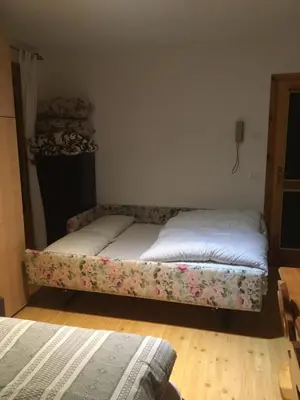 two beds in a room with avertisement for at Monolocale DORI in Alleghe