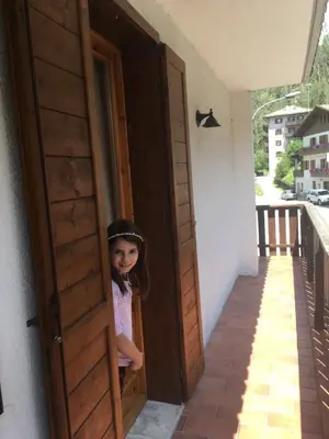 a little girl is looking out of a door at Monolocale DORI in Alleghe