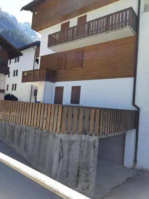 a building with a wooden fence in front of it at Monolocale DORI in Alleghe