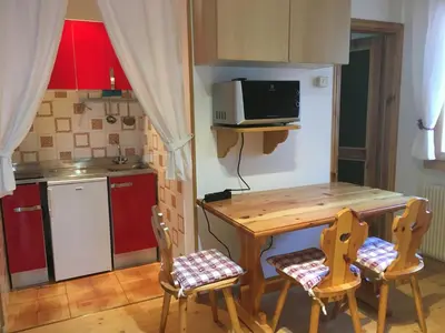 a small kitchen with a wooden table and chairs at Monolocale DORI in Alleghe