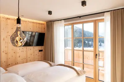 a bedroom with two beds and a large window at Penserhof - Alpine Hotel & Restaurant in Sarntal