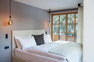 a bedroom with a white bed with a window at Penserhof - Alpine Hotel & Restaurant in Sarntal