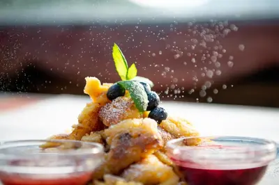 a plate of food with blueberries and sauce at Penserhof - Alpine Hotel & Restaurant in Sarntal