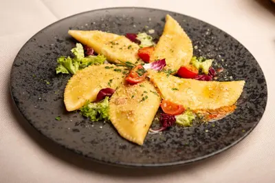 a black plate with food on a table at Penserhof - Alpine Hotel & Restaurant in Sarntal