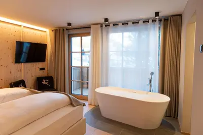 a bedroom with a tub in front of a window at Penserhof - Alpine Hotel & Restaurant in Sarntal